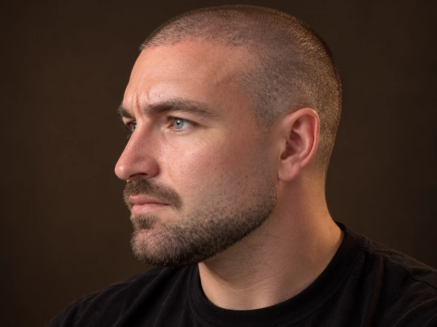 Man met een buzz cut en een korte, verzorgde baard, van opzij gezien