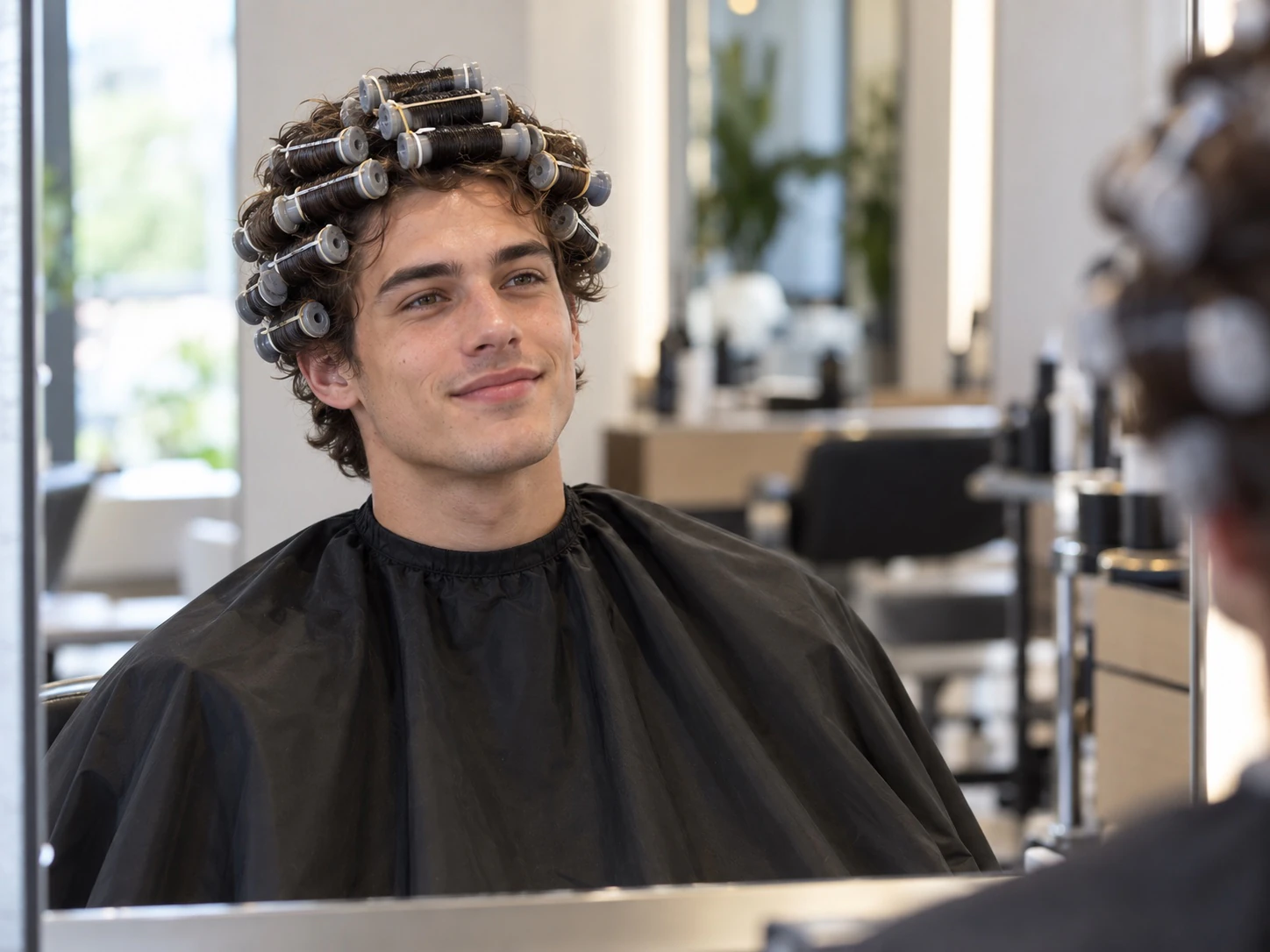 Man in de kappersstoel met zijn haar bovenop om krulspelden gedraaid, van opzij gezien